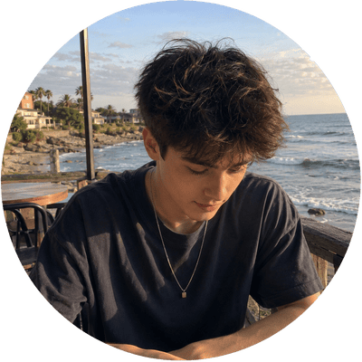 A round user profile icon displaying a young man in a dark shirt sitting on a coastal boardwalk, ideal for a social discovery and connection app